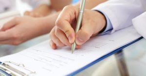 doctor writing on clipboard