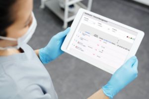 Female doctor holding Ipad with Universal Patient Link logo on screen